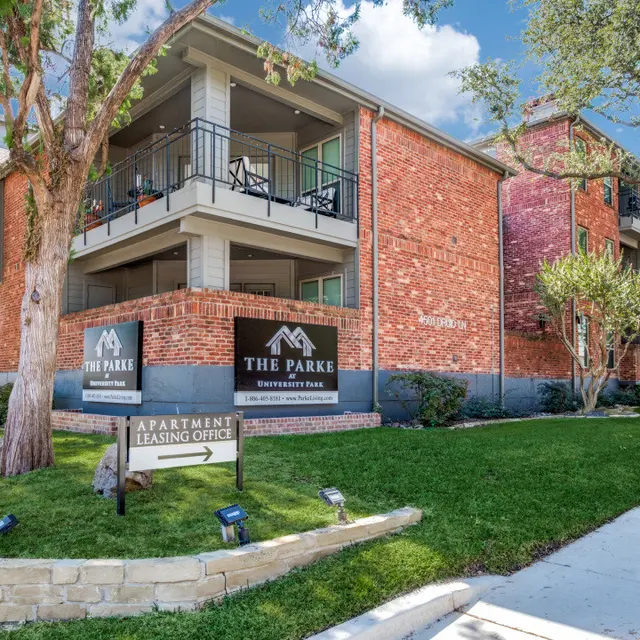 The Parke Apartment Complex Exterior view of The Parke apartment complex with green grass and trees around.