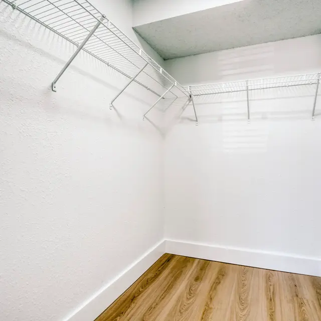 Empty Closet with Wire Shelving An empty closet with white walls and wooden flooring featuring wire shelving.