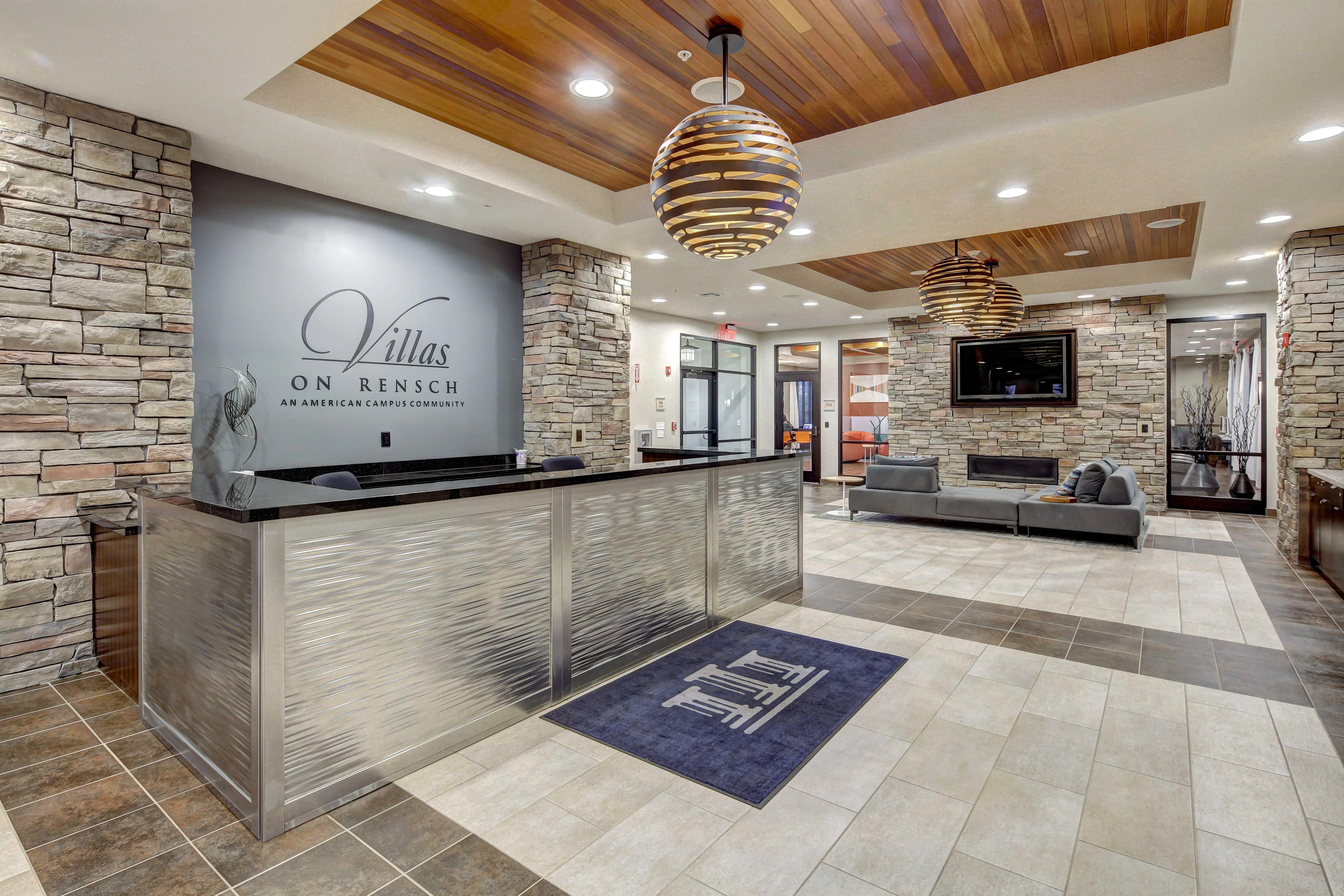 Modern lobby of Villas on Rensch featuring a stone wall, a sleek reception desk, and stylish lighting fixtures.