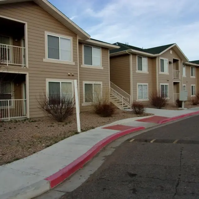 Apartment Building Exterior Exterior view of an apartment building with several units, featuring beige siding, multiple windows, and small plants in the landscape.