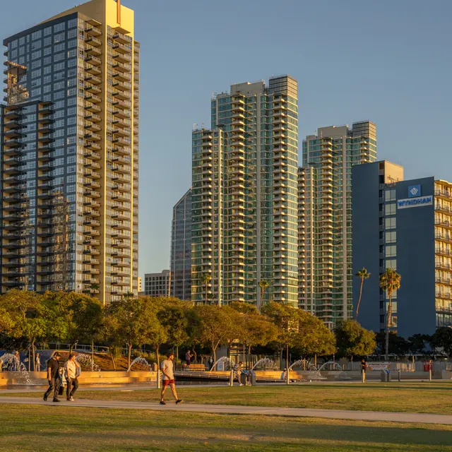 Modern urban landscape featuring tall buildings and green park space during sunset.