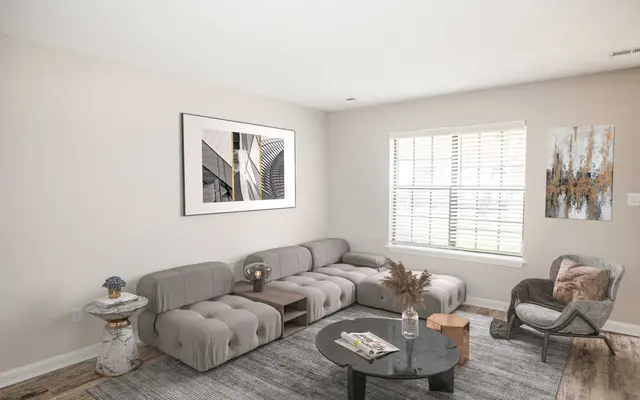 Summit at 501 Stylish living room with a gray sectional sofa, coffee table, decorative items, and art pieces on the walls, brightened by natural light.