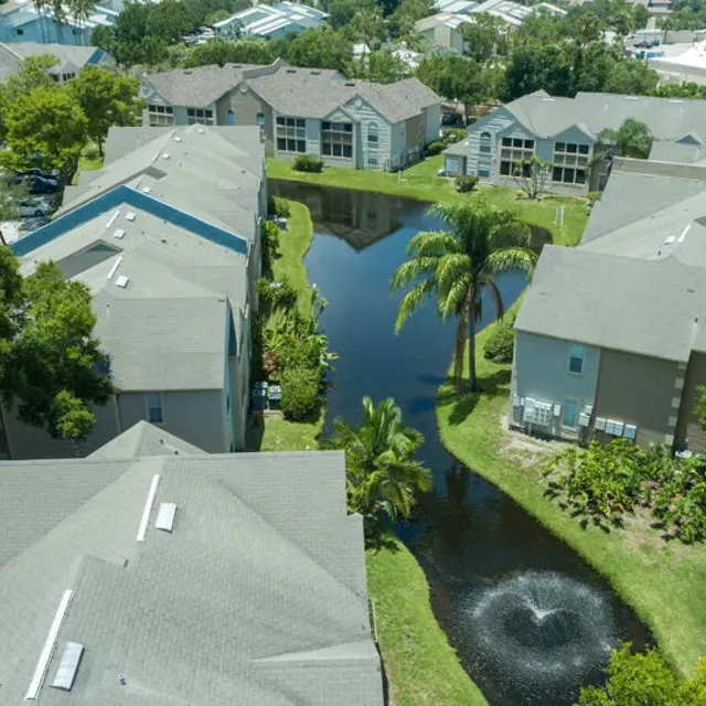 Aerial view of the apartment buildings, trees, lake and water fountain at Bradenton Reserve.  