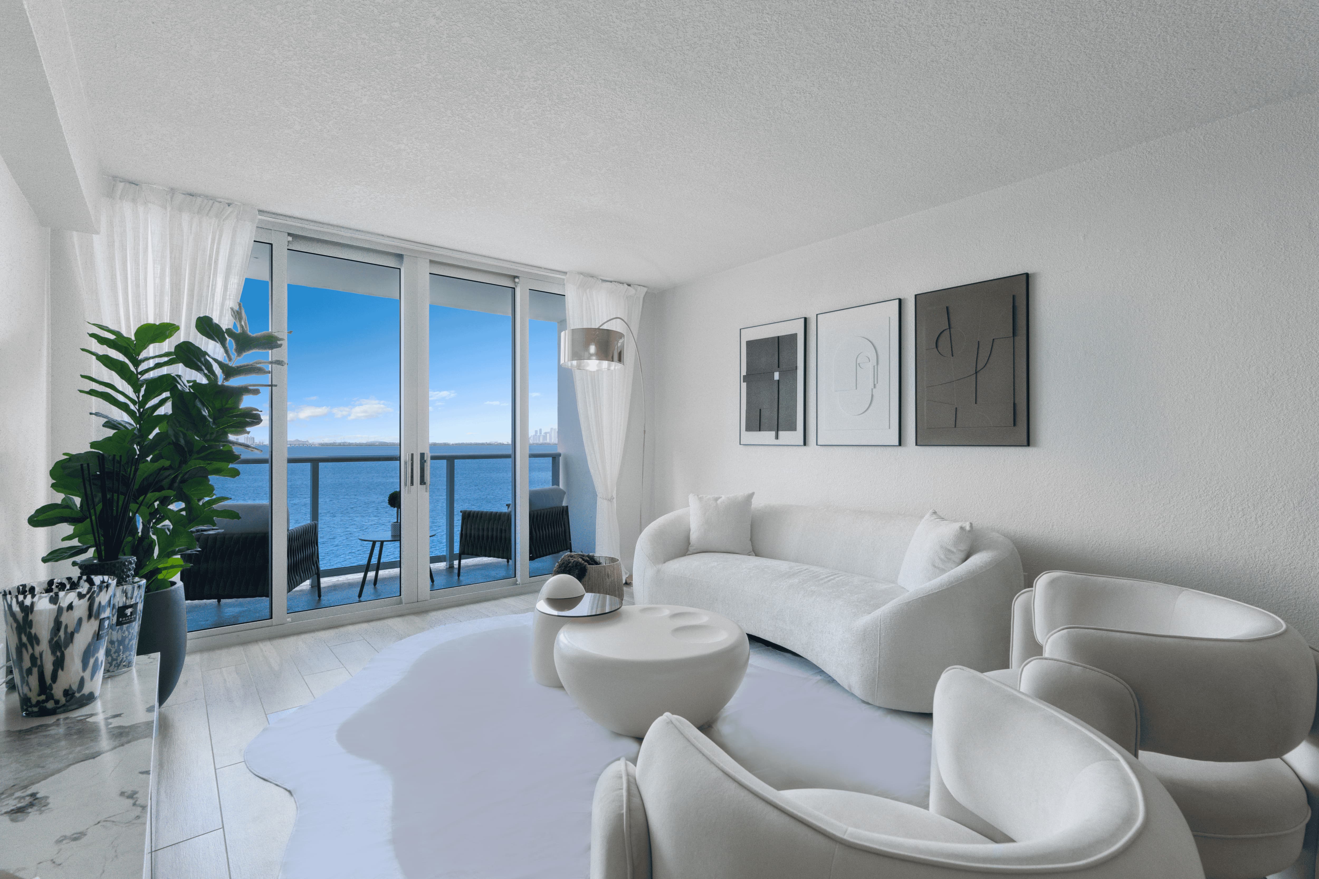 Modern Living Room with Ocean View A modern living room featuring a white curved sofa with matching chairs, a round coffee table, and a large window showcasing an ocean view.