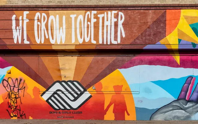 WE GROW TOGETHER A vibrant mural featuring the phrase 'WE GROW TOGETHER' with colorful artistic elements including silhouettes and abstract shapes.