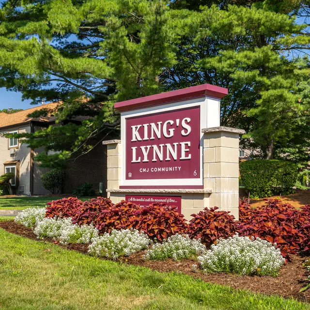 Sign for King's Lynne community surrounded by flowers and greenery.