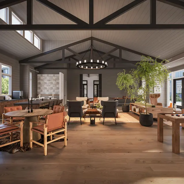 A spacious, modern living room featuring high ceilings with exposed beams, large windows allowing natural light, a combination of seating areas, and decorative plants.