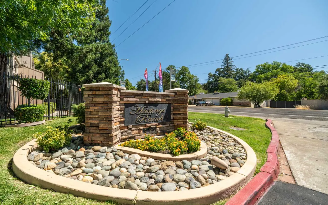 A stone sign with the name 'Gateway Park' in a landscaped area with rocks and greenery, under a clear blue sky.