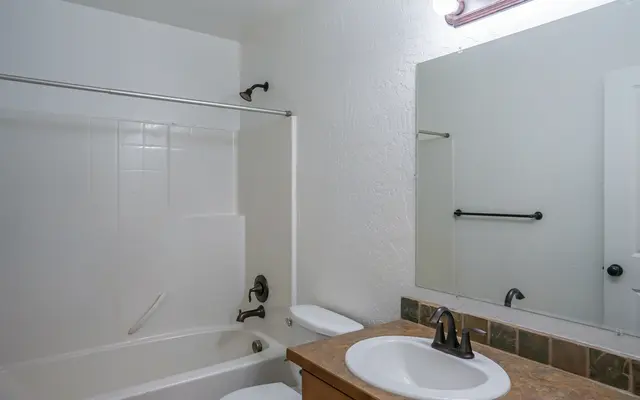 Modern Bathroom Overview A clean, simple bathroom featuring a bathtub with a shower curtain, a white sink with a brown countertop, and a wall-mounted mirror above the sink.