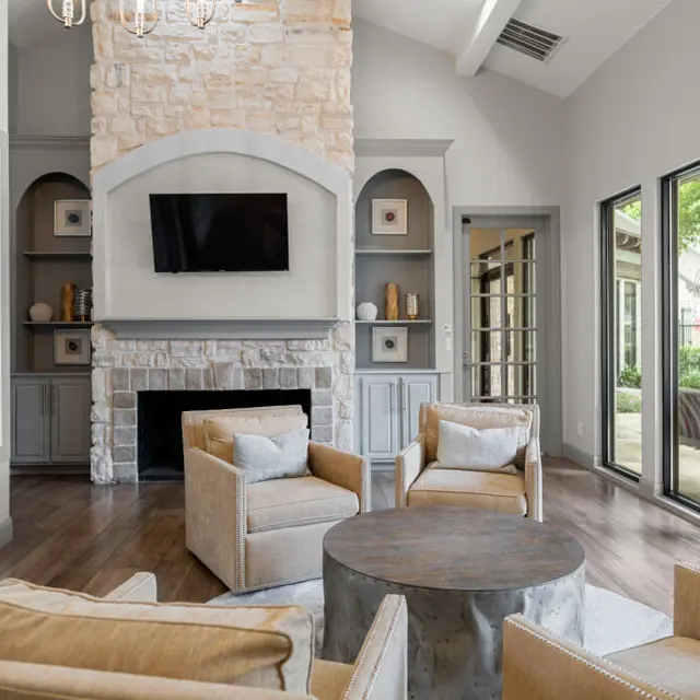 A contemporary living room featuring a stone fireplace, a mounted TV, and comfortable seating arranged around a round coffee table.