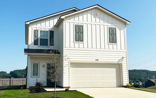 A modern two-story house with a white exterior and green window shutters, featuring a garage and well-maintained lawn.