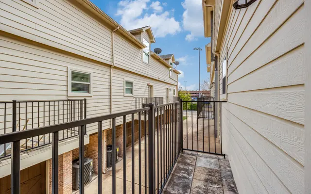 Balcony View of Adjacent Buildings A view from a balcony overlooking a walkway between two buildings with light-colored siding.