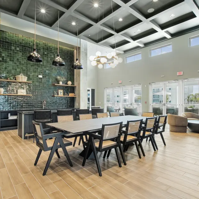 Modern interior of a spacious dining area with a large table, pendant lights, and walls adorned with decorative tiles.