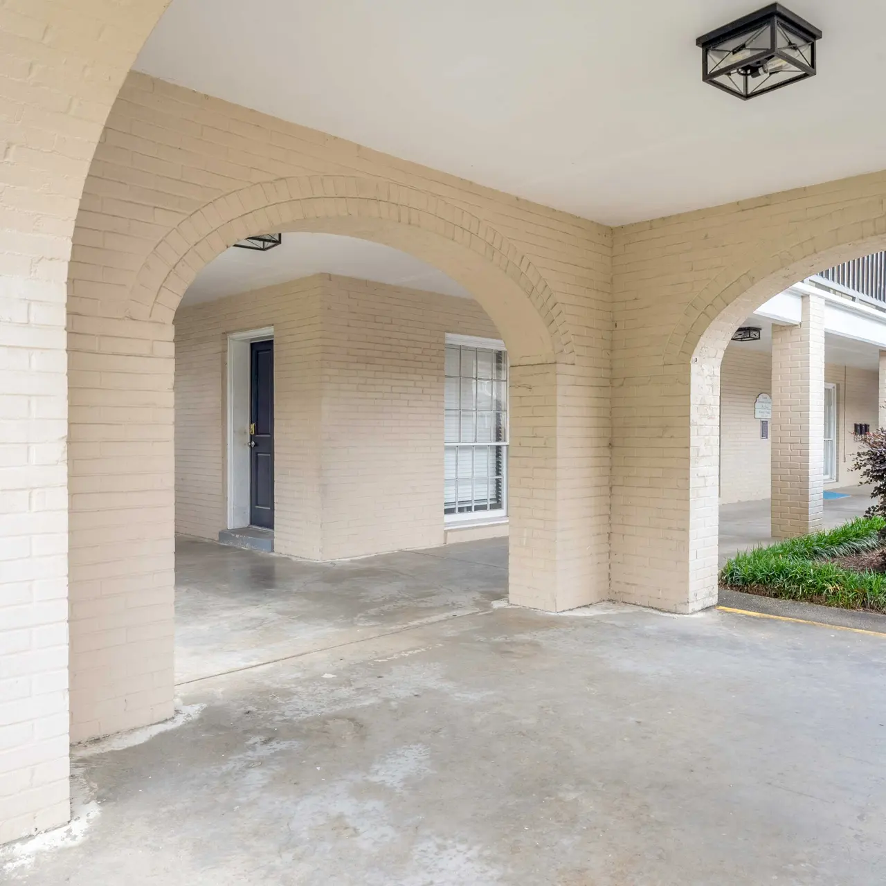 View of a covered courtyard area featuring archways and greenery.