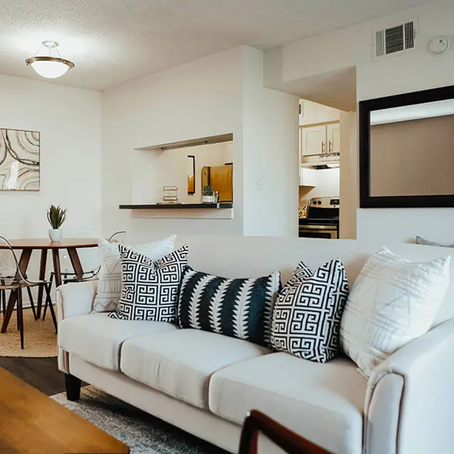 Furnished living room and dining room with white walls and hardwood-style flooring.