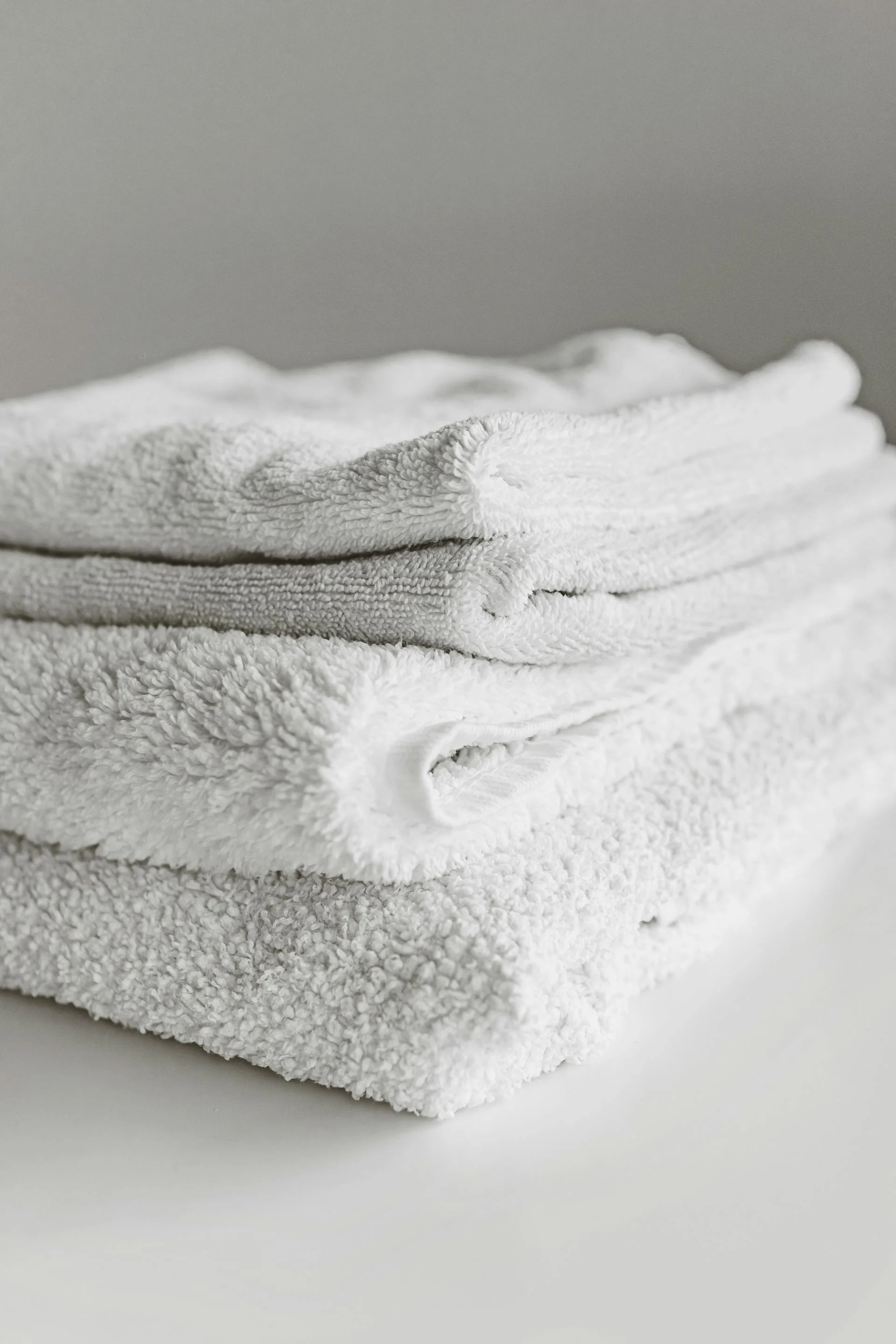 Neatly Folded White Towels A neatly folded stack of white towels on a light surface