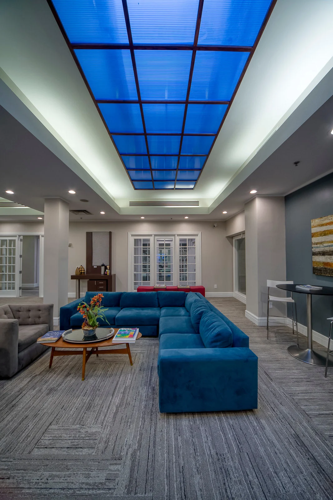 Modern lounge area with a blue sectional sofa and bright skylight