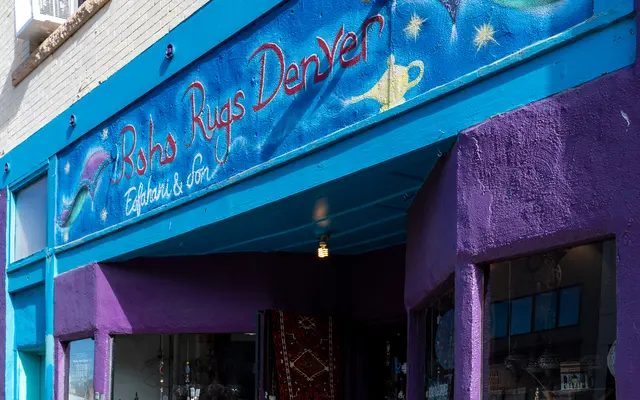 Exterior view of a store named 'Robs Rugs Denver' with colorful signage and a purple wall.