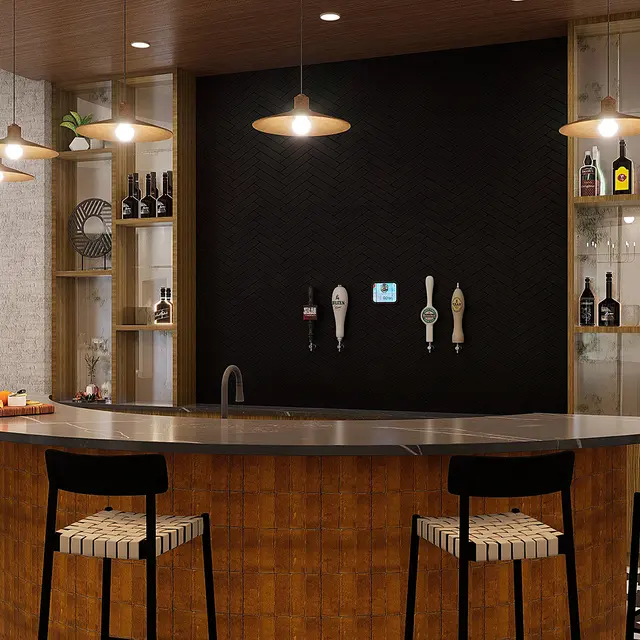 A modern home bar with a curved countertop, high stools, and a black accent wall featuring taps and decorative shelves.