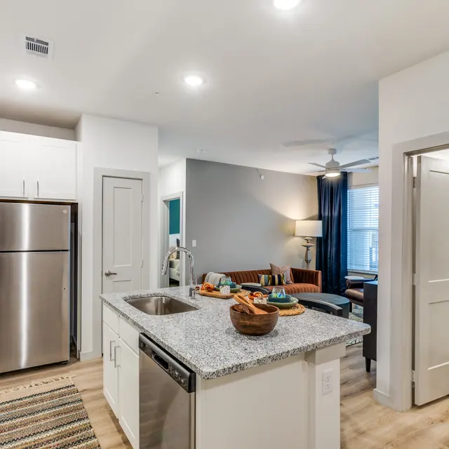 A well-lit modern kitchen and living area with an island, stainless steel appliances, and a cozy seating area.
