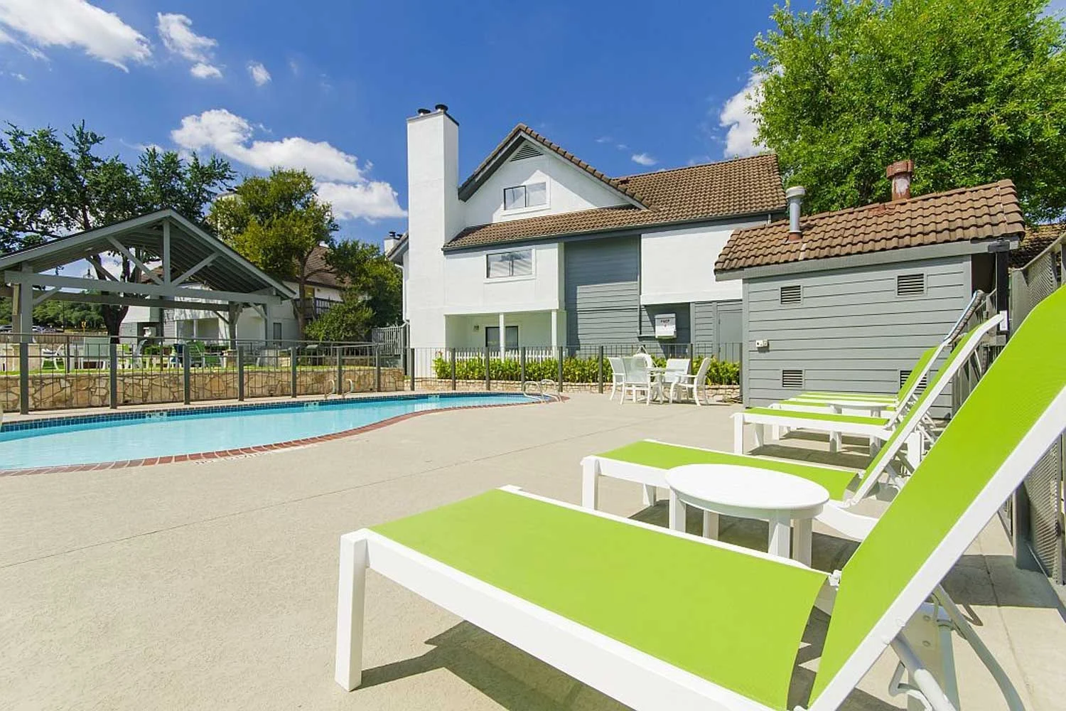 Lime green lounge chairs and patio chairs and table at resident pool at Edge Studios