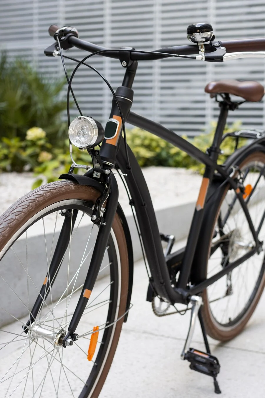 Sleek Urban Bicycle A sleek modern bicycle featuring a black frame and brown accents, equipped with a front light, set against a stylish urban background.