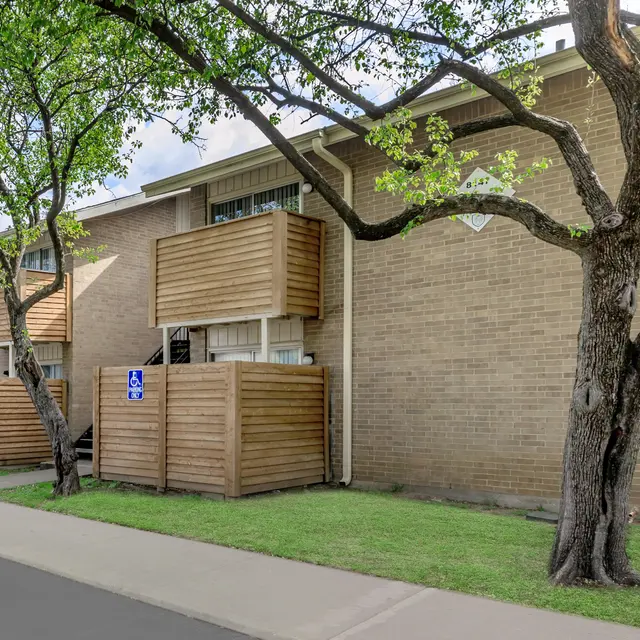 Residential Apartment Complex Exterior view of an apartment complex with wooden balconies and trees.