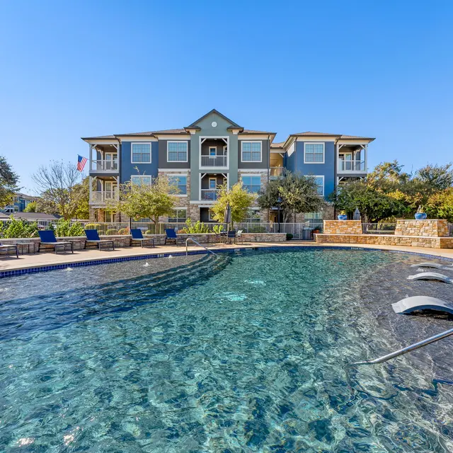 Pool area of an apartment complex with a clear blue sky.