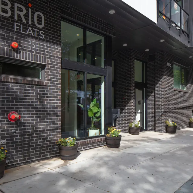 Brio Flats Entrance Exterior view of Brio Flats building, featuring a sleek modern design and a landscaped entryway with planters.