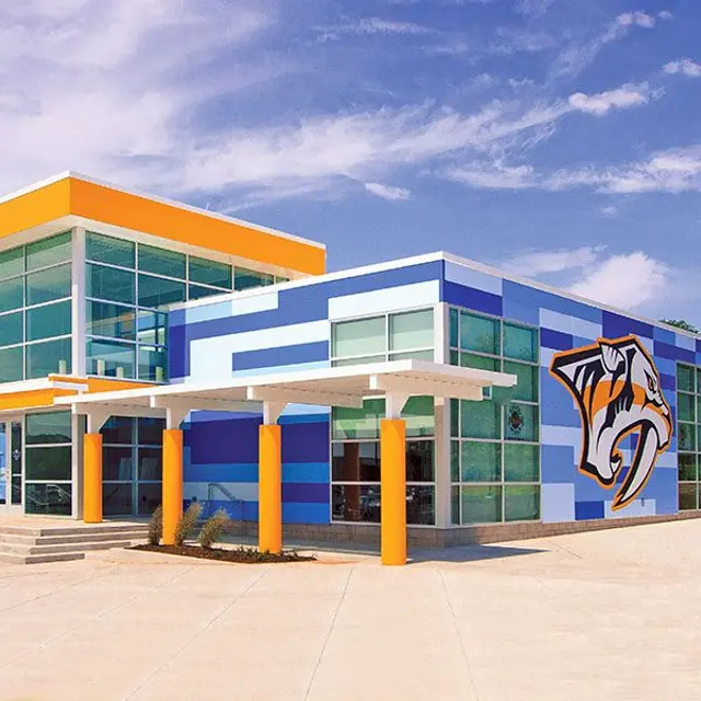 A modern building with a blue and orange facade, featuring large glass windows and a striking graphic of a tiger's head on one side.