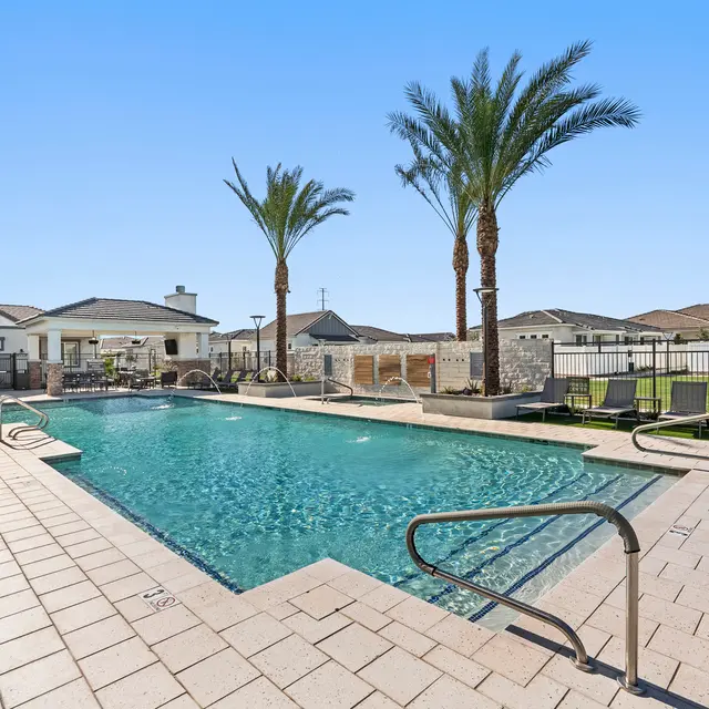 Lush Poolside Oasis A serene swimming pool surrounded by palm trees and comfortable lounge chairs under clear blue skies.