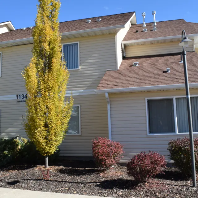 Apartment Building Exterior Exterior view of a two-story apartment building with a staircase, surrounded by shrubs and decorative plants.