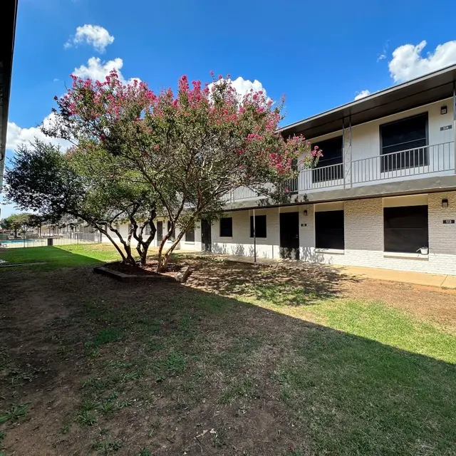 Apartment Complex Landscape View of an apartment complex with two-story buildings and a small lawn area featuring a flowering tree.