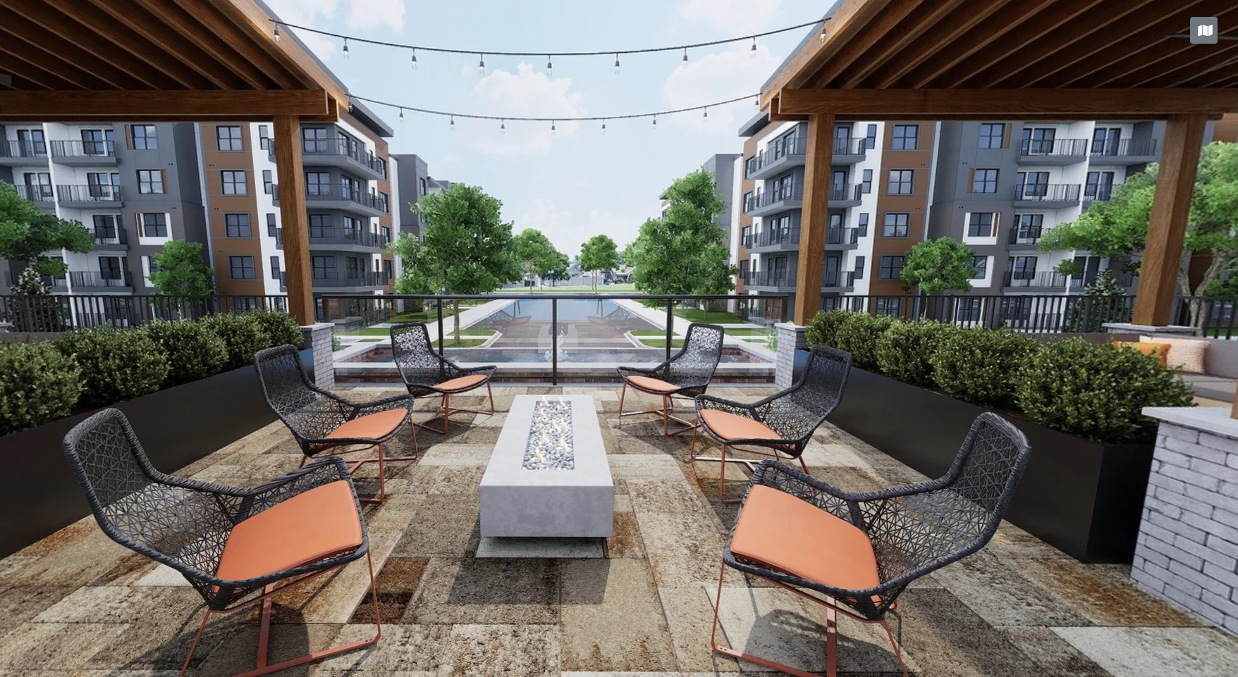 District Eastside An outdoor lounge area featuring multiple chairs and a fire pit, surrounded by greenery and apartment buildings in the background.
