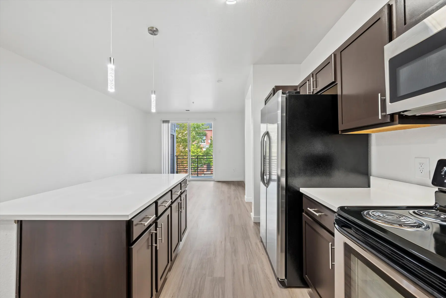 A modern kitchen featuring dark cabinetry, stainless steel appliances, and a large island with a white countertop.