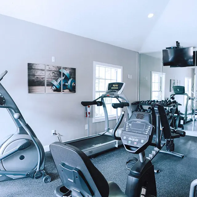 Fitness center with cardio equipment, and two large windows for natural lighting at Bradenton Reserve. 