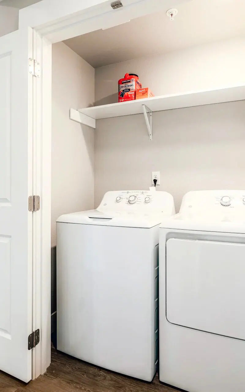 The front view of a modern washer and dryer set in a laundry room, featuring overhead storage space