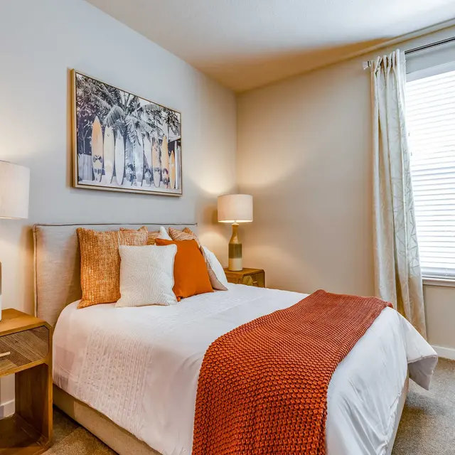 ShoreView A bedroom at ShoreView Waterfront Apartments with a large window and carpet flooring.