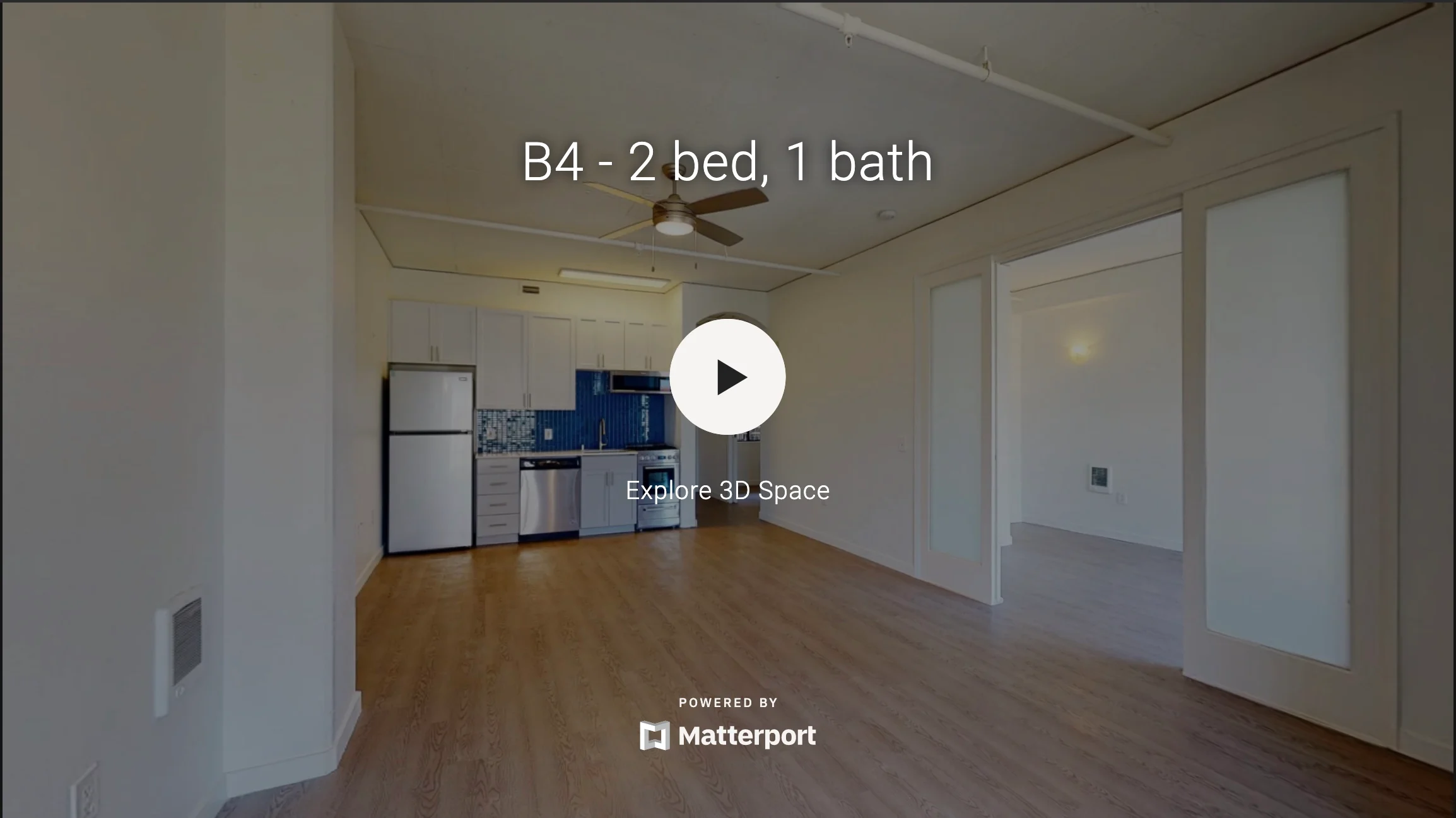 Interior view of a modern apartment with a kitchen area, featuring a refrigerator, kitchen cabinets, and an open living space.