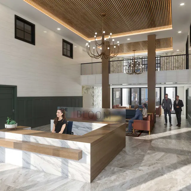 A modern lobby featuring a reception desk with a woman seated, elegant chandelier, and cozy seating areas. The interior showcases a blend of wood and marble materials with large windows.