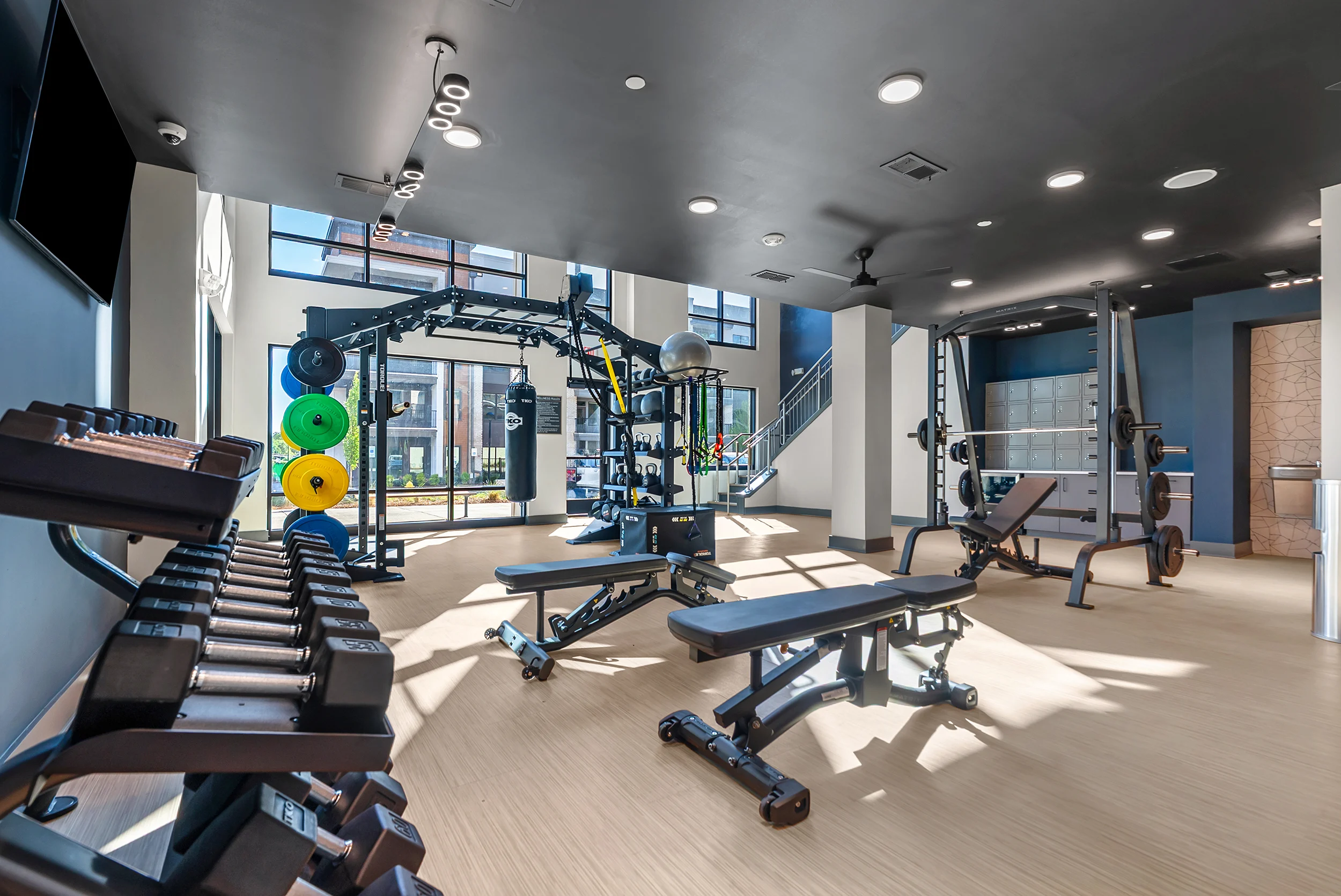 Interior view of a modern gym with weights, bench presses, and various workout equipment.