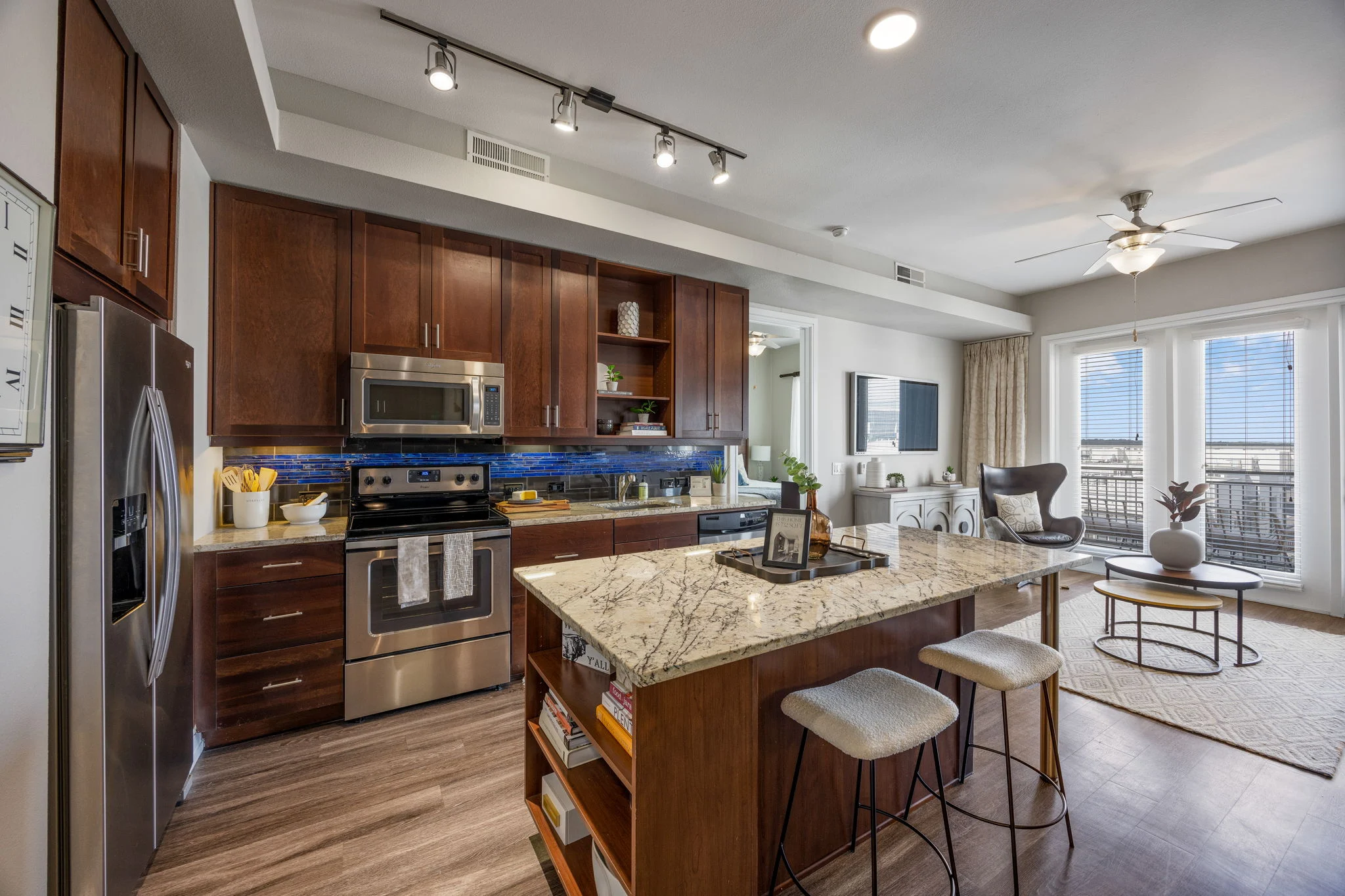 Modern Kitchen Interior A modern kitchen featuring dark wood cabinetry, stainless steel appliances, and a large granite island with seating. Natural light comes in from large windows, providing a cozy and inviting atmosphere.