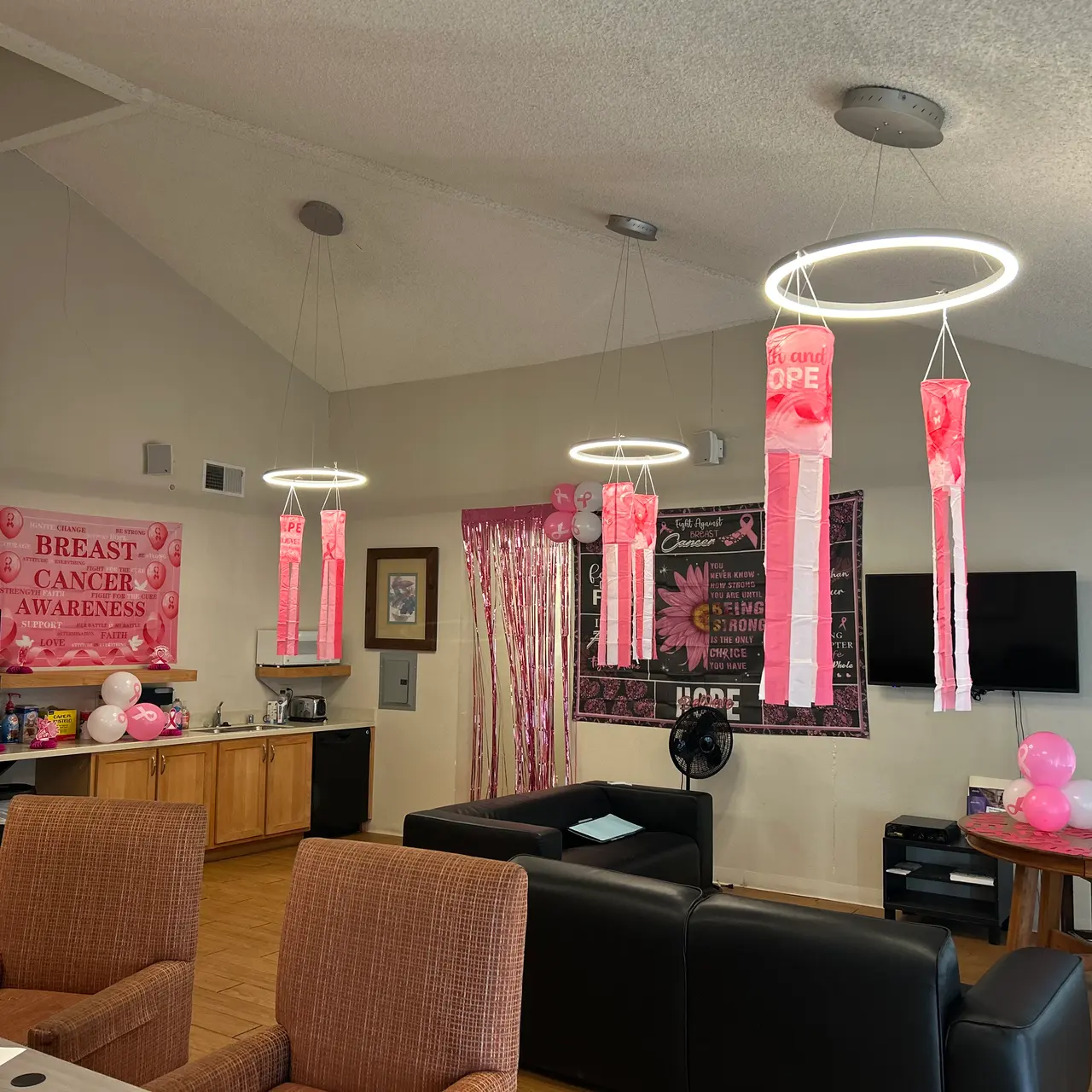 Interior of a room decorated for Breast Cancer Awareness Month, featuring pink decorations, banners, and hanging lanterns.