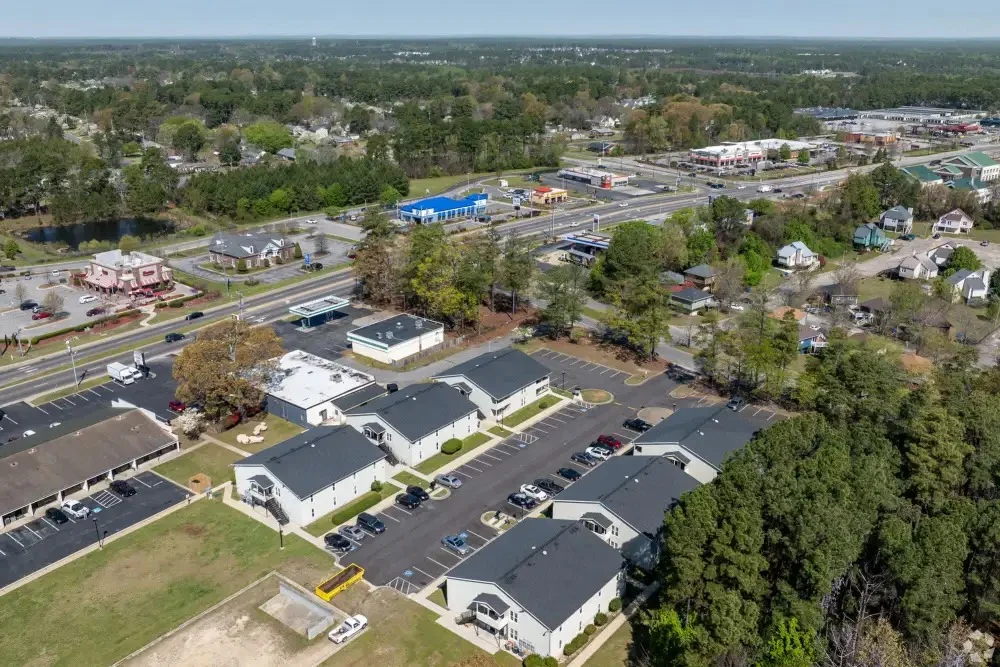 Aerial View of a Suburban Area Aerial view of a suburban area featuring residential buildings, a parking lot, and roads running through the landscape.
