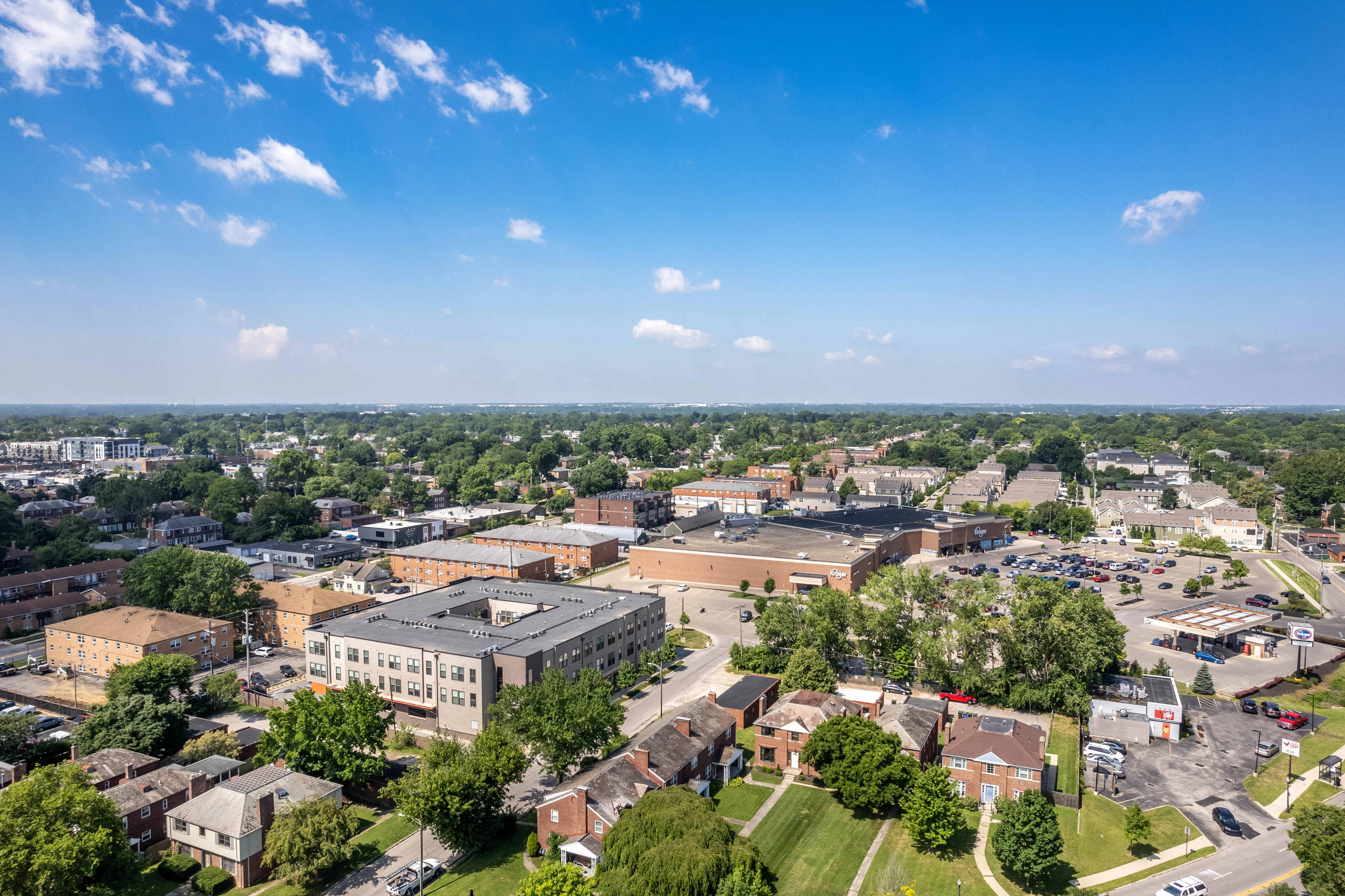 Suburban Landscape Aerial View Aerial view of a suburban area featuring a mix of residential and commercial buildings, green areas, and blue skies with a few clouds.