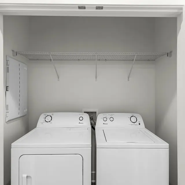 A washer and dryer side by side in a laundry closet with shelves above.