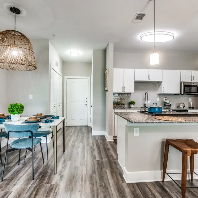 Centreport Lake Furnished model apartment on hardwood-style flooring, kitchen island and stove with light gray walls.