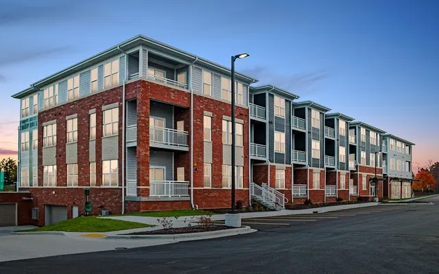 Modern three-story apartment building with balconies during twilight.