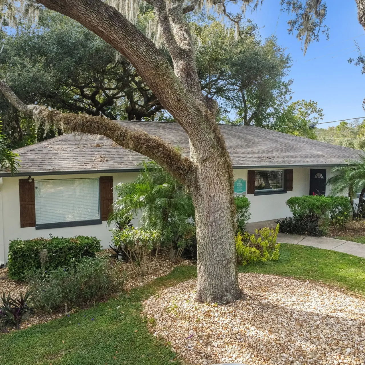 The exterior area of an apartment in our community, fitted with a garden, tall trees, and a paved walkway