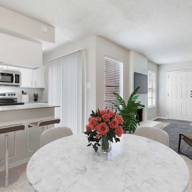 Open apartment floor plan with view into kitchen from dining area, breakfast bar with stools, and living area with a couch and a fireplace